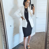 woman wearing black tank dress with a white blazer standing in mirror
