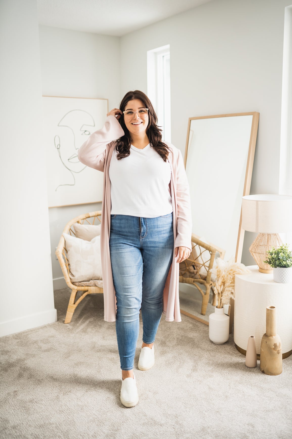 woman wearing long pink cardigan and white v-neck t-shirt and jeans