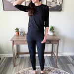 woman standing wearing black long sleeved t shirt and black tapered joggers