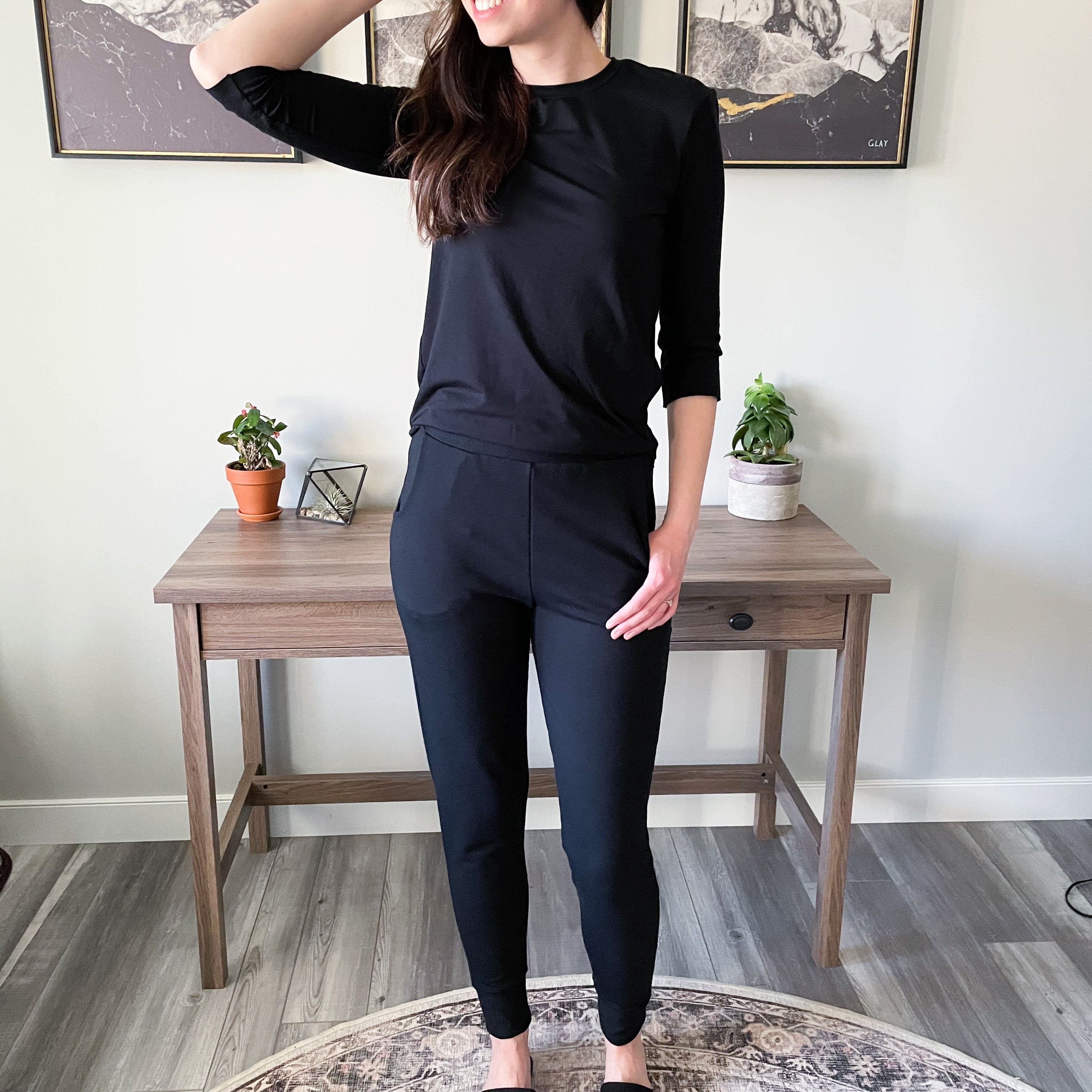 woman standing wearing black long sleeved t shirt and black tapered joggers
