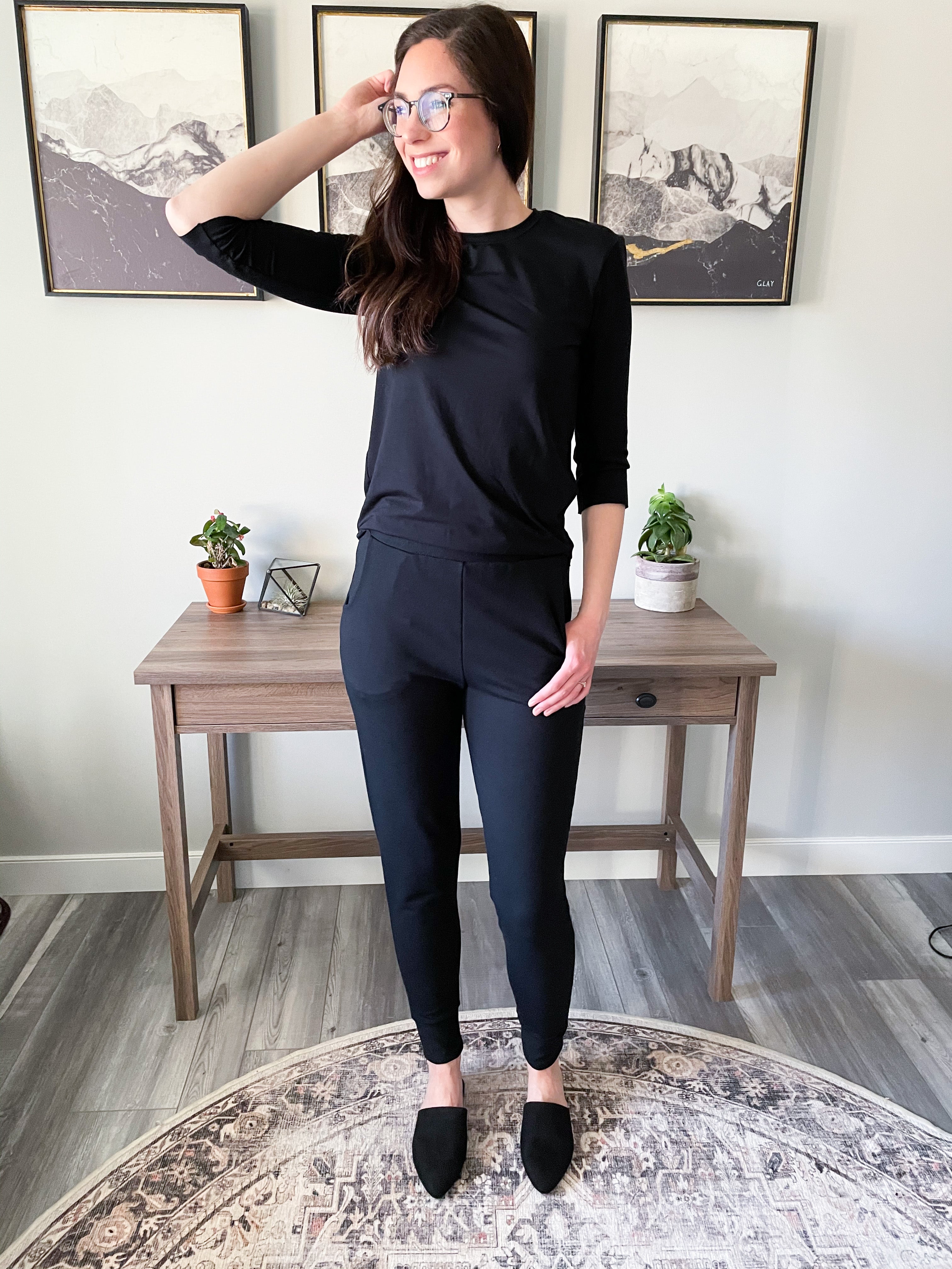 woman standing wearing black long sleeved t shirt and black tapered joggers