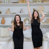two woman smiling and dancing wearing black tank dresses 