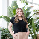 blonde woman wearing black t shirt in front of plant