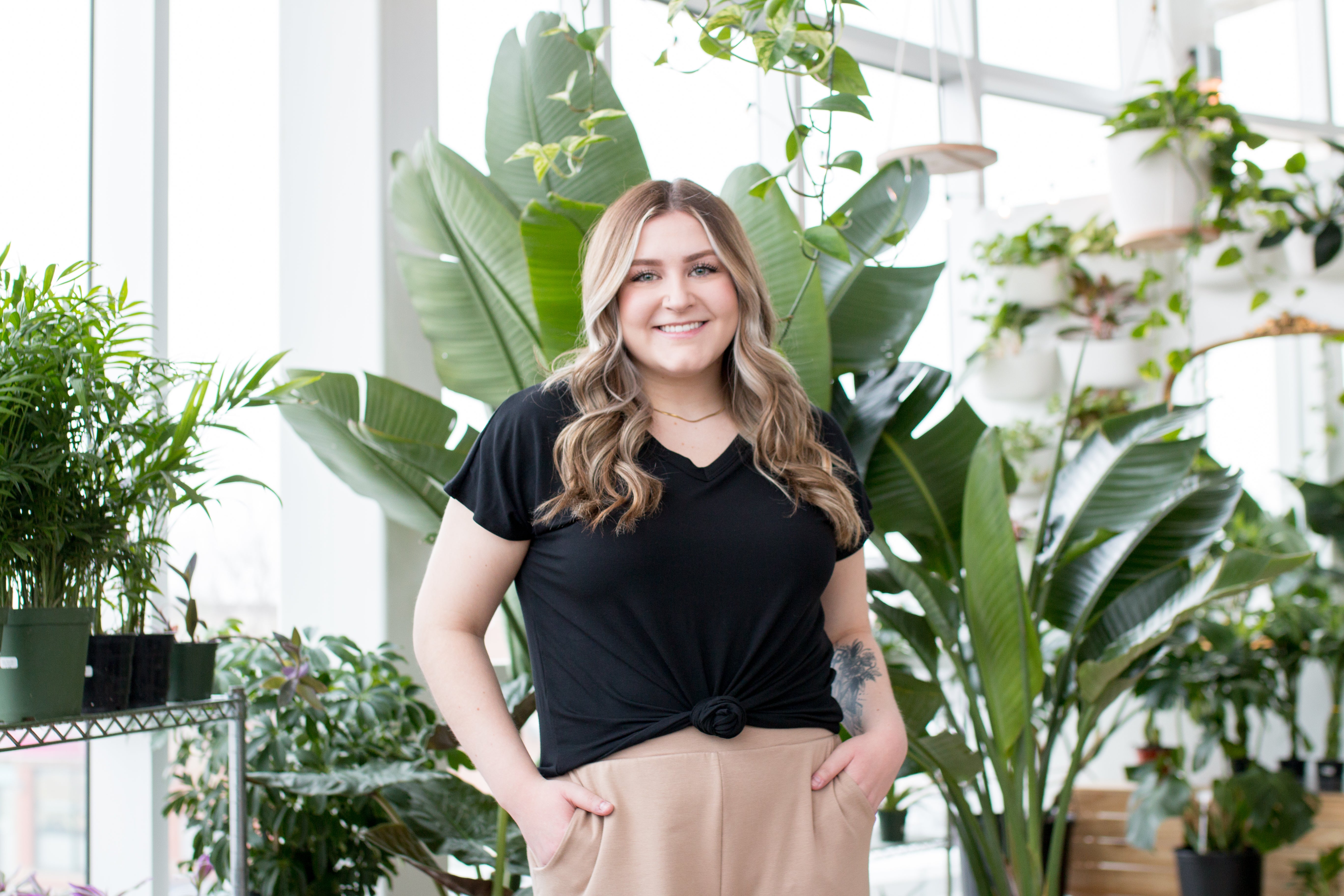 blonde woman wearing black t shirt in front of plant