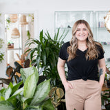 blonde woman standing in black vneck t shirt and beige joggers