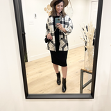 woman wearing plaid shacket, black midi tank dress and a tan hat standing in front of a mirror