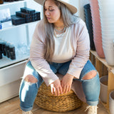 woman sitting wearing a pink cardigan and cream sweater with a hat