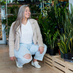 woman smiling wearing white t-shirt jeans and a beige jacket