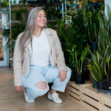 woman smiling wearing white t-shirt jeans and a beige jacket