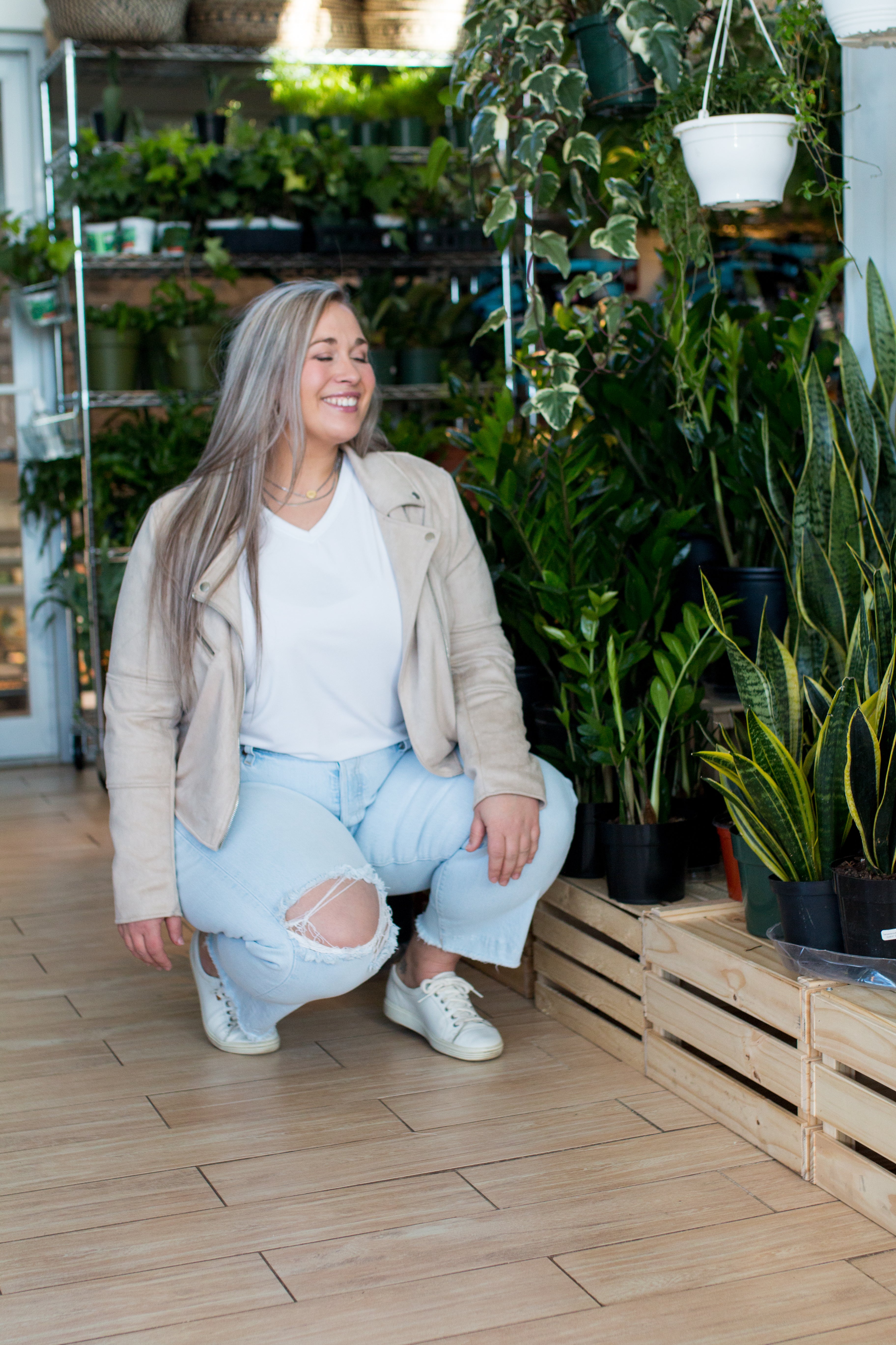 woman smiling wearing white t-shirt jeans and a beige jacket
