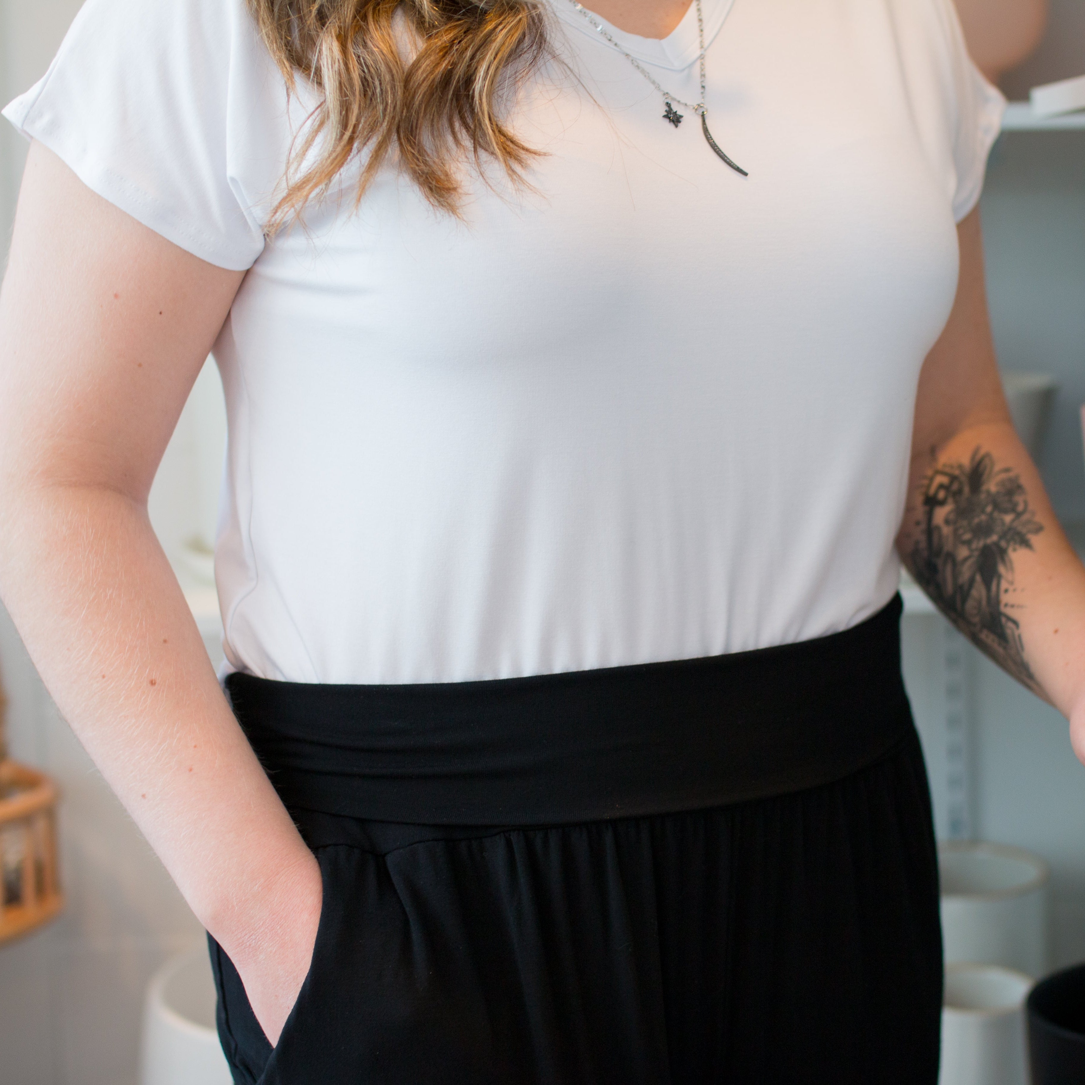 close up photo of woman wearing a white vneck tshirt and black wide leg pants. close up photo of waistband