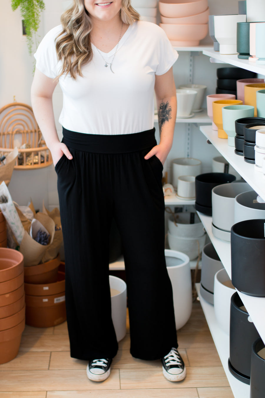 woman wearing a white vneck tshirt and black wide leg pants