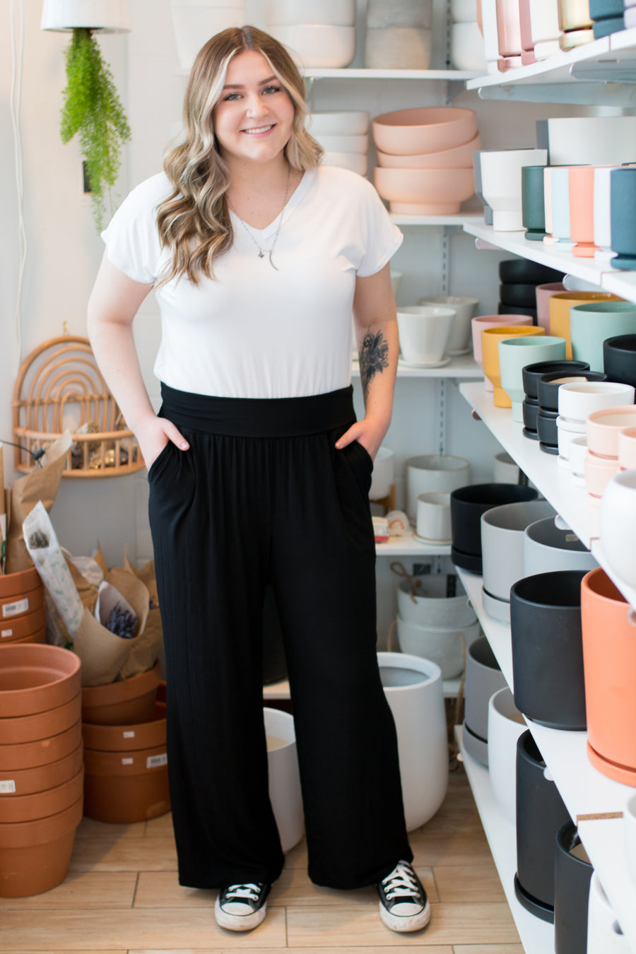 woman wearing a white vneck tshirt and black wide leg pants